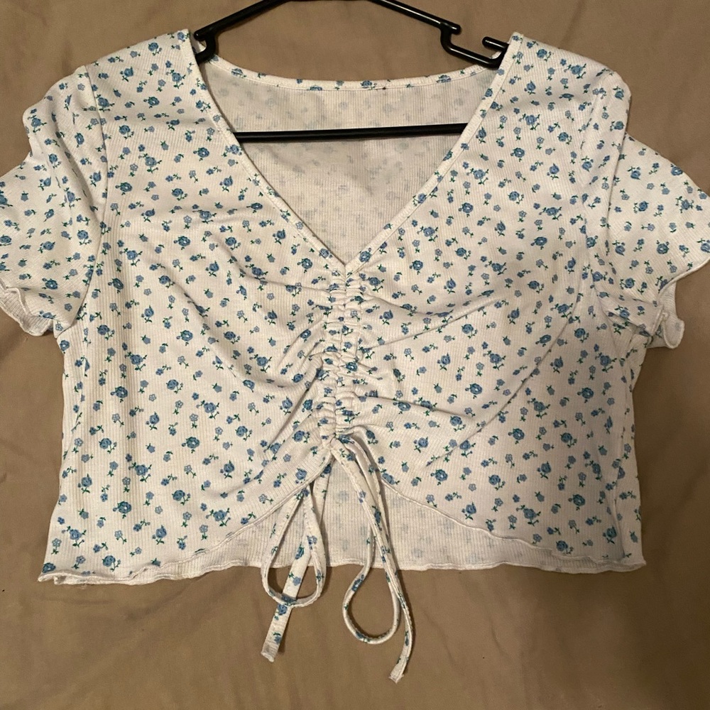 white cropped shirt with blue flowers all over and adjustable tied front scrunch